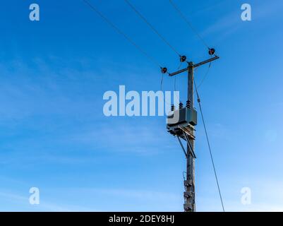Wooden telegraph poles with wires and insulators against a clear blue sky background Stock Photo