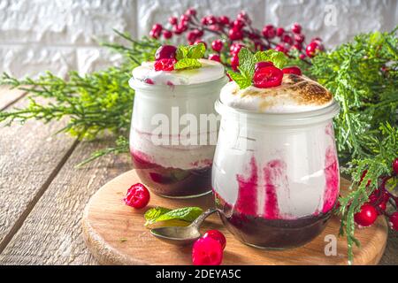 Cranberry layered Dessert breakfast in small jars for Christmas morning. Homemade baked Cranberry meringue dessert, with fresh cranberries and mint, c Stock Photo