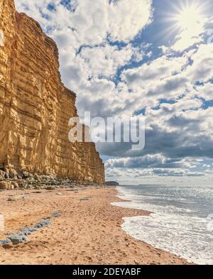 The imposing and eroded sandstone cliffs exposing millions of years of sedimentary geological layers. West Bay in Dorset on the Jurassic coast. Stock Photo