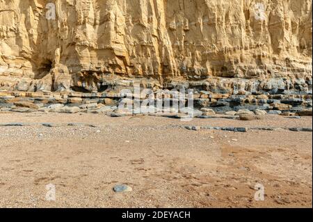 The imposing and eroded sandstone cliffs exposing millions of years of sedimentary geological layers. West Bay in Dorset on the Jurassic coast. Stock Photo