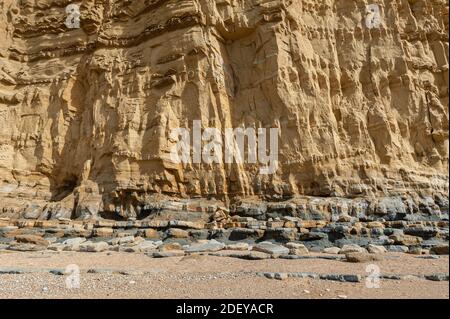 The imposing and eroded sandstone cliffs exposing millions of years of sedimentary geological layers. West Bay in Dorset on the Jurassic coast. Stock Photo