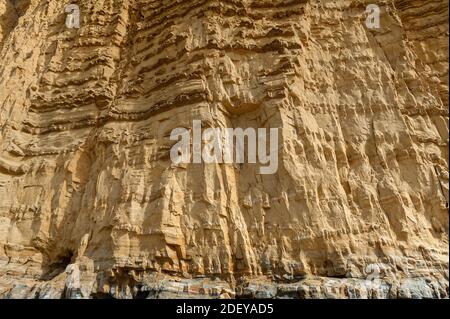 The imposing and eroded sandstone cliffs exposing millions of years of sedimentary geological layers. West Bay in Dorset on the Jurassic coast. Stock Photo