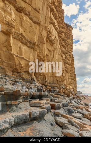 The imposing and eroded sandstone cliffs exposing millions of years of sedimentary geological layers. West Bay in Dorset on the Jurassic coast. Stock Photo