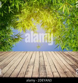Wood plank with abstract natural blurred bamboo forest and blue sky  background for product display Stock Photo