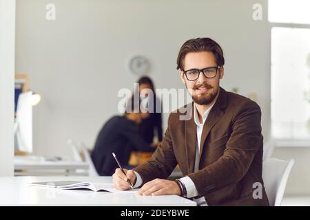 Portrait of modern hipster businessman working in modern office on workers background. Stock Photo
