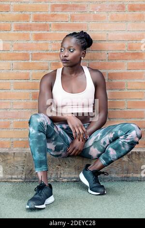 Stock photo of an African-American sprinter standing in front of a building wall Stock Photo