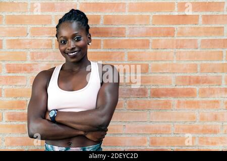 Stock photo of an African-American sprinter smiling standing in front of a building wall looking at camera straight ahead Stock Photo