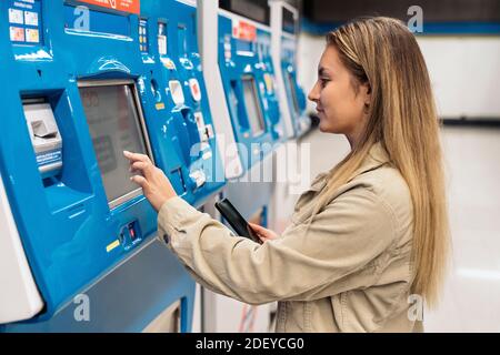 Stock photo of young blonde woman buying a metro ticket in the machines. Stock Photo