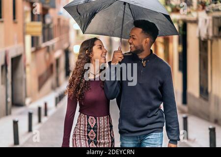 Stock photo of happy moment of interracial couple of lovers having fun in the street. They are in Madrid city Stock Photo