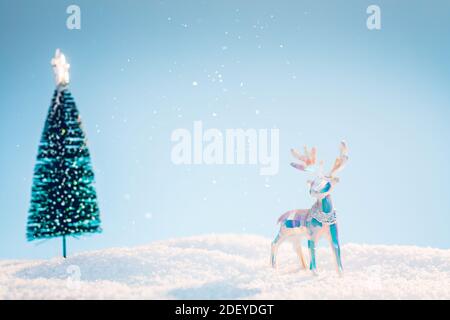 Multicolored polygonal christmas deer in snow on light blue sky background Stock Photo