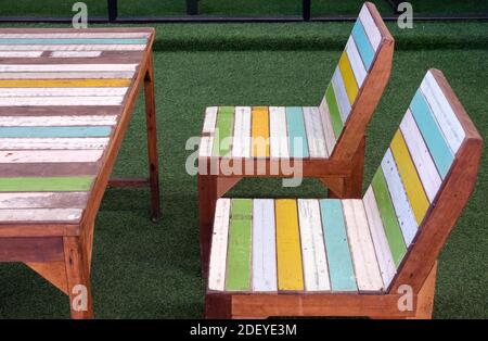 Side view of the painted plank chair and table set in the retro style, on the artificial grass in front of the cafe. Stock Photo