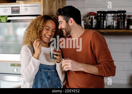 Stock photo of a middle aged woman and man standing in a kitchen and smiling. They are going to kiss. Stock Photo