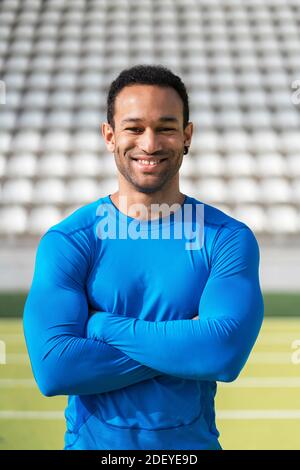 Stock photo of african american athlete in akimbo arms looking at camera in running track. Stock Photo