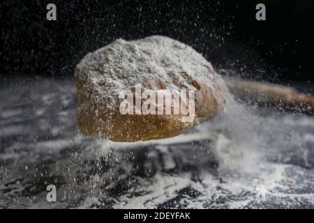 Bread flying with flour splash on floury black table.Creative concept of bakery, baking and cooking .Copy Space. Stock Photo