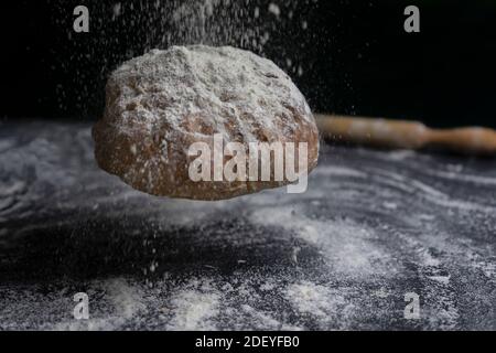 Bread flying with flour splash on floury black table.Creative concept of bakery, baking and cooking .Copy Space. Stock Photo