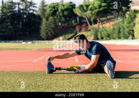 Disabled man athlete stretching with leg prosthesis. Paralympic Sport Concept. Stock Photo