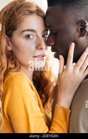 Stock photo of multiethnic young couple hugging and kissing. Stock Photo