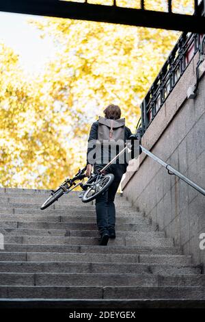 Stock photo of unrecognized man going up the stairs with his bike. Stock Photo