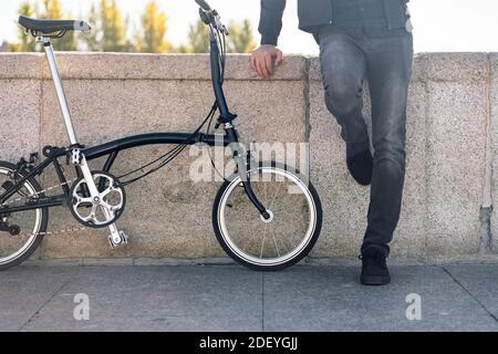 Stock photo of faceless man standing in the street next to his removable bike. Stock Photo