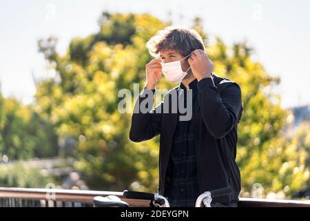 Stock photo of handsome man putting on his face mask in the street. Stock Photo