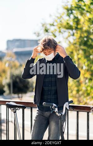 Stock photo of handsome man putting on his face mask in the street. Stock Photo