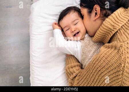 Stock photo of young mother kissing her little baby and sharing cute moment. Stock Photo
