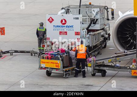 Aircraft ramp loader loading baggage to conveyor belt on airport apron ...