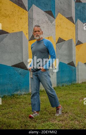 Shot of a stylish handsome man walking in front of a colorful wall Stock Photo