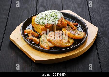 Potato casserole with fried pork mini belly slices on dark wooden table Stock Photo