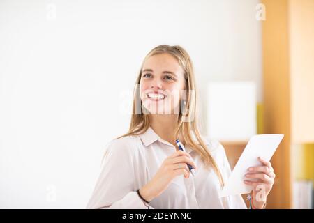 young woman with pencil and folio in an office working Stock Photo