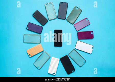 Pile of multicolored plastic back covers for mobile phone on blue background. Choice of smart phone protector accessories. A lot of silicone phone bac Stock Photo