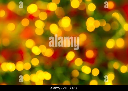 Bokeh yellow led lighting on a blurred red green background. Defocused lights of an electric garland. Decoration and design element for holidays. Stock Photo