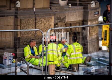 London, UK - June 22, 2018: Street road with people workers eating lunch on break at construction site in downtown city Stock Photo