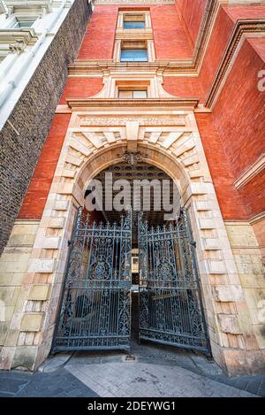 London, UK - June 24, 2018: Victoria and Albert art museum Henry Cole wing building entrance through cast iron gate with Victorian red brick architect Stock Photo
