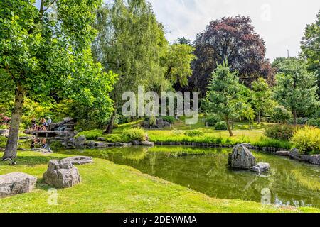 London, UK - June 24, 2018: People in summer at Kyoto Garden park with lush green tree foliage, lake pond and tiered waterfall in United Kingdom Stock Photo