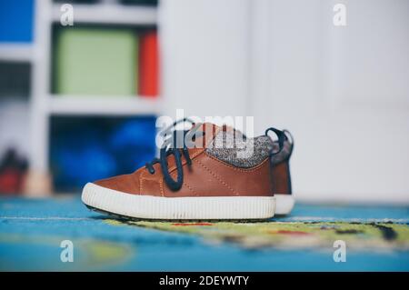 A selective focus shot of a pair of kid's shoes on a carpeted floor Stock Photo