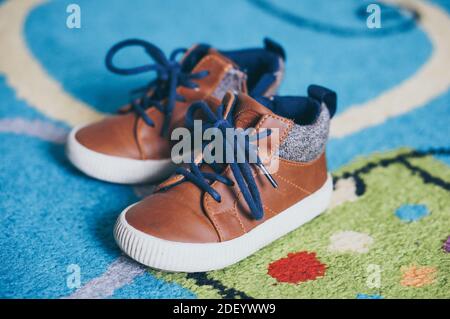 A selective focus shot of a pair of kid's shoes on a carpeted floor Stock Photo