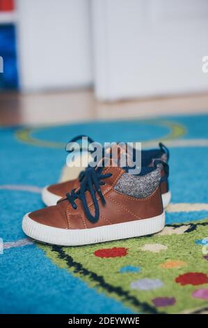 A vertical selective focus shot of a pair of kid's shoes on a carpeted floor Stock Photo