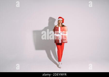Pretty woman with wrapped Christmas present. Christmas gift wrapped in red paper with white bow.. Stock Photo