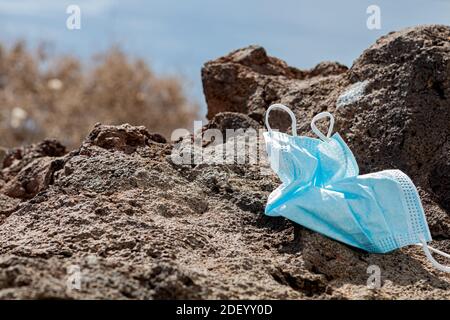 Surgical mask thrown away on a rock facing the sea. Close up, horizontal