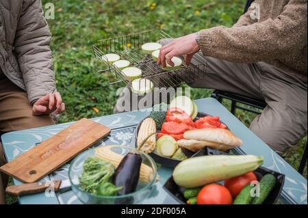 Still life shot, hands cutting vegetables on a cutting board. Preparing for a family dinner on the lawn in front of a country house. Summer activities Stock Photo