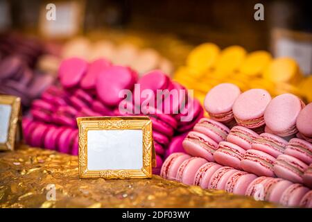 Display of gourmet colorful bright pink and red macaroons macarons on shelf window tray in bakery store shop Stock Photo