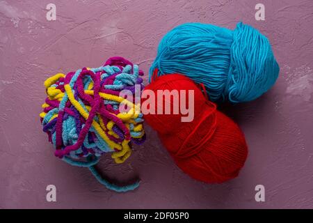 balls of multi-colored threads for knitting on a pink background Stock Photo