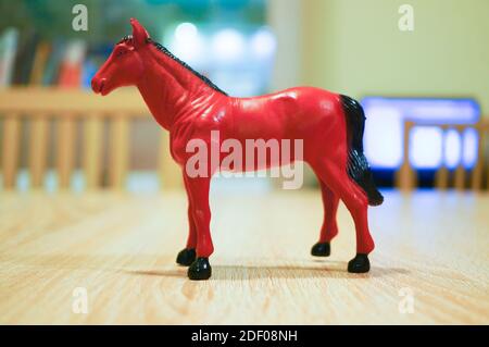 A closeup shot of a red horse plastic toy on a wooden surface Stock Photo
