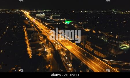 Closeup night traffic road with cars, trucks aerial. Philippines capital town of Manila cityscape. Urban scenery of metropolis city close up. Modern buildings with illuminated highway on bridge Stock Photo