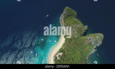 Top down ocean island aerial view. Tropical forest with palm trees on mount of Palawan isle, Philippines. Epic nature landscape of paradise resort at white sand beach. Asia sea bay drone shot