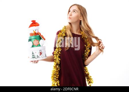 Pensive young woman, wearing a Santa Claus hat, dreams, looking to the side, in her hands, a gift box on a white background. Christmas Stock Photo