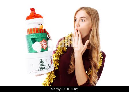 Shocked woman in Santa Claus hat looking at a Christmas present with a surprise, on a white background. Christmas Stock Photo