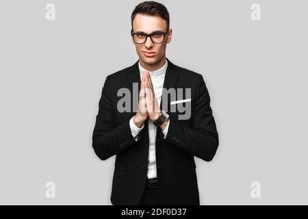 Portrait of a handsome young business man, male, in a classic black suit, shows poses on gray background. Business concept, career. Stock Photo