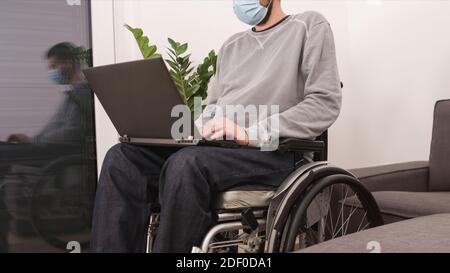 Man on wheelchair remotely working from home using laptop, looking at screen with virtual web chat. Stock Photo